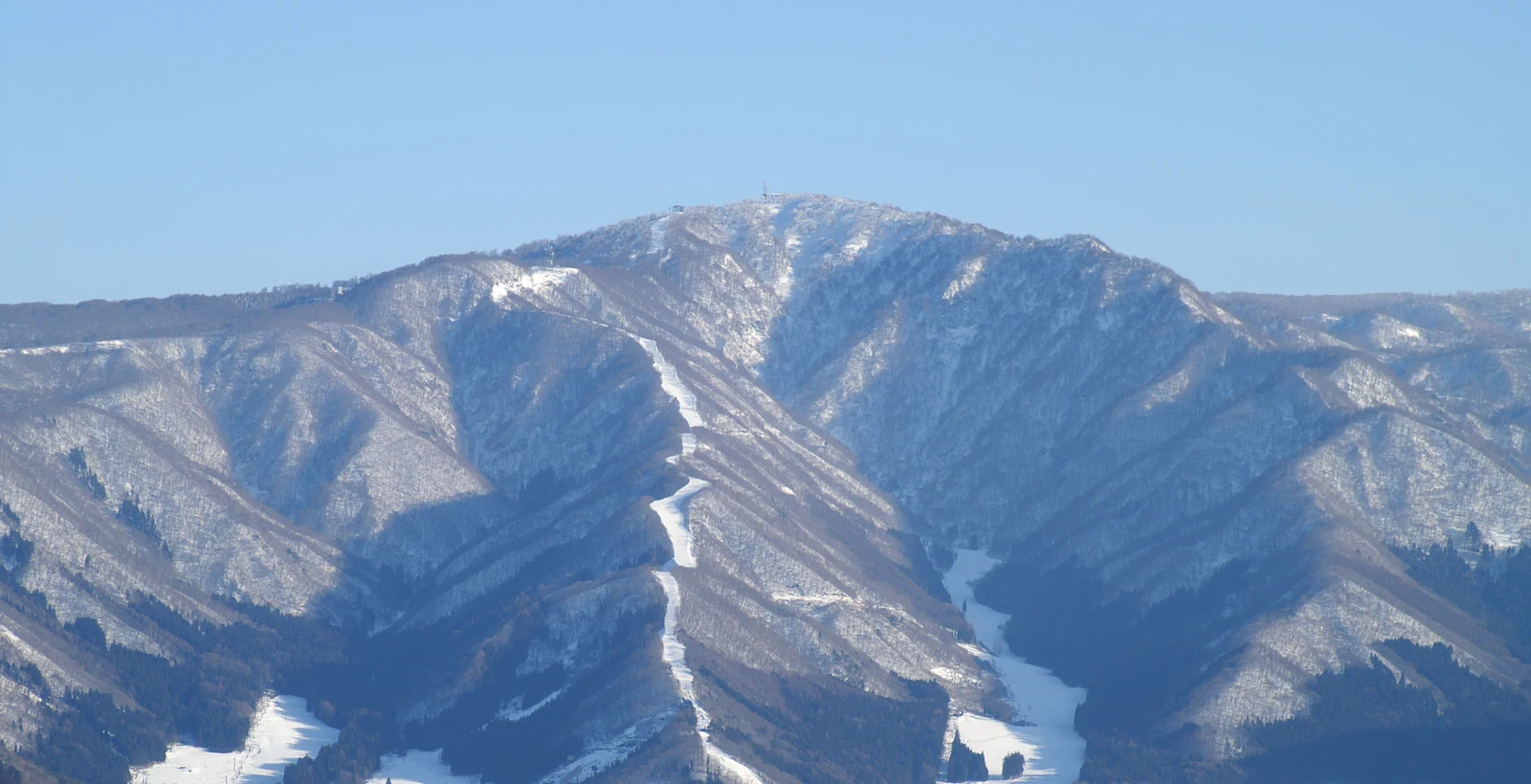 Snow-covered Mount Kenashi and wooded ridgelines above Nozawa Onsen